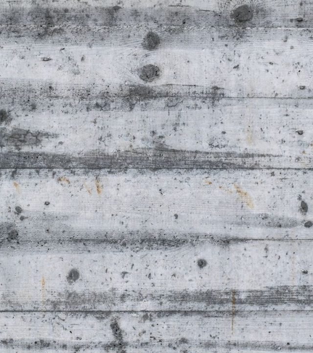 Detailed view of a gray textured concrete wall with wood patterns and imperfections.